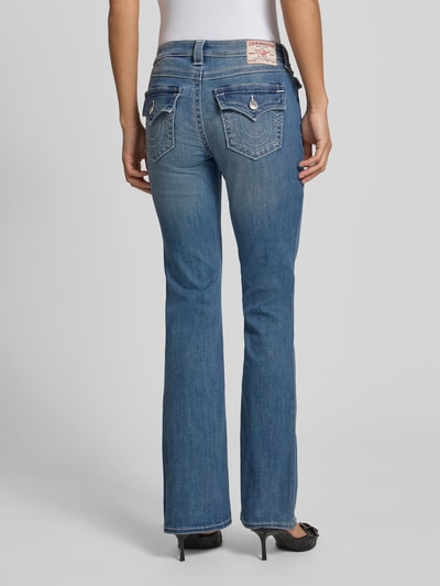 Frauenmodel trägt Mid Rise Bootcut Jeans im Used-Look Modell 'BECCA' von TRUE RELIGION aus Baumwoll-Mix mit Stretch-Anteil, mittelblaue Jeans-Optik, rückseitige Ganzkörperansicht.