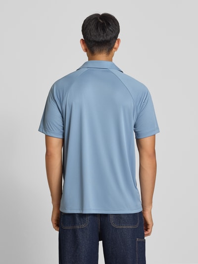 Mężczyzna nosi koszulkę polo Relaxed Fit Poloshirt mit Logo-Stitching od Champion, jasnoniebieska, wyhaftowane logo, krój relaxed fit, kołnierzyk polo, z krótkim rękawem, długość tyłu w rozmiarze M: 70 cm, całkowity widok z tyłu.