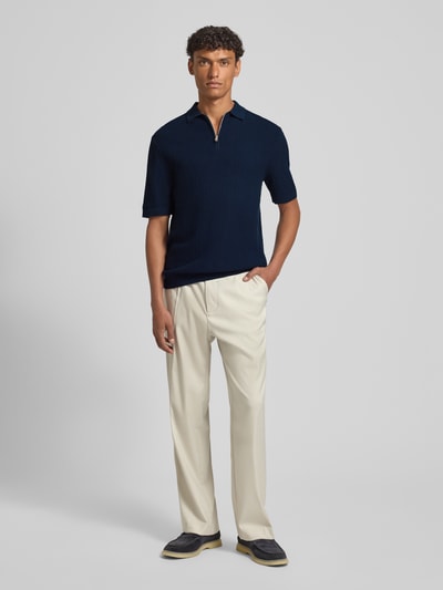 Męski model nosi Regular Fit Poloshirt aus reiner Bio-Baumwolle Modell 'CRAN' od SELECTED HOMME, granatowa struktura, krój regular fit, strickoptik, krótki rękaw, polokragek, zamek, bawełna organiczna, widok całej sylwetki z przodu.