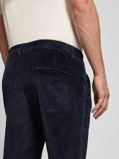 Männermodel trägt dunkelblaue Straight Fit Hose aus Baumwoll-Mix Modell 'Chasy' von DRYKORN mit Cord-Optik, Nahaufnahme Rückansicht.