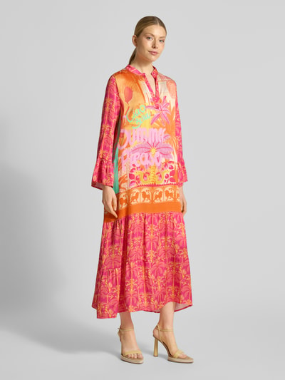 Kobiece modelka nosi sukienka midi z wiskozy z dekoltem w serek model 'Orange Palm' od miss goodlife, linia a, wzór na całej powierzchni, długość tyłu w rozmiarze s: 130 cm, szerokość w rozmiarze s: 53 cm, długość rękawów w rozmiarze s: 58 cm, pomarańczowy i różowy, widok całej sylwetki z przodu.