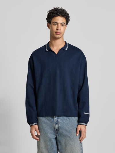 Mannelijk model draagt Strickpolo uit pure katoen model 'JORNIAGARA' van Jack & Jones, los vallende fit, V-hals, labeldetail, voorkant totaalbeeld.