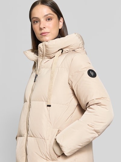 Frauenmodel trägt Regular Fit Mantel in Stepp-Optik Modell 'Nova' von MOS MOSH in Beige, sichtbare Kapuze, Eingrifftaschen, Nahaufnahme Oberkörper. Damen Mantel von MOS MOSH, Zweiwege-Reißverschluss, Rückenlänge 102 cm, Schulterbreite 42 cm, Brustweite 46 cm, Ärmellänge 64 cm.