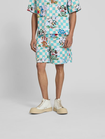 Mannelijk model draagt Shorts mit Allover-Motiv-Print van Kenzo in turquoise-wit, puur katoen, relaxed fit, elastische band, knoop- en ritssluiting, all-over motiefprint; Ganzkörperansicht van voren.