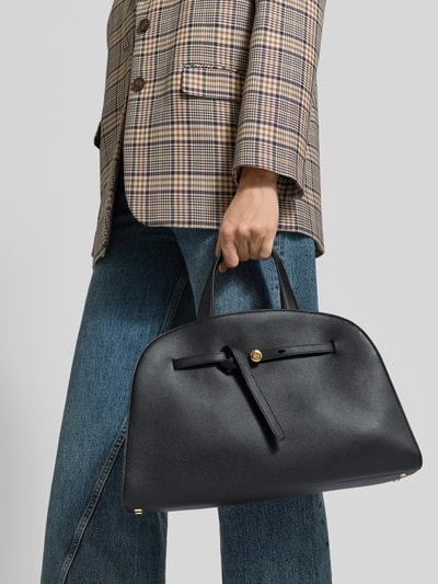 Vrouwenmodel draagt Crossbody Bag met karabijnsluiting van Tory Burch in zwart leer met Labeldetail, Binnenvak met ritssluiting, afneembare schouderband en draagband, formaat Breedte 35 cm, Lengte 24 cm, Diepte 13 cm, Ganzkörperansicht van voren.