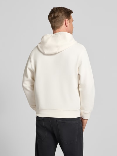 Männermodel trägt Sweatjacke mit Zweiwege-Reißverschluss Modell 'FELPA' von ARMANI EXCHANGE aus Baumwoll-Mix in Offwhite, Relaxed-Fit, Kapuze, Label-Detail und Eingrifftaschen, Rückenlänge 67 cm, Ärmellänge 58 cm, Ganzkörperansicht Rückansicht.