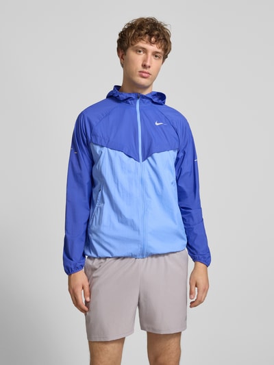 Männermodel trägt Trainingsjacke mit Logo-Print und Kapuze von NIKE TRAINING in Blau mit Reißverschluss, geradem Schnitt, Ganzkörperansicht von vorne.