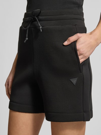 Frauenmodel trägt Regular Fit Shorts aus Viskose-Mix von Guess Activewear in Schwarz mit elastischem Bund und Eingrifftaschen, Nahaufnahme Oberkörper.