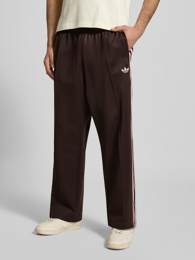 Männermodel trägt Straight Fit Sweatpants mit Logo-Stitching Modell 'Firebird' von adidas Originals aus Baumwoll-Mix, Ziernaht, elastischer Bund, Ganzkörperansicht von vorne.