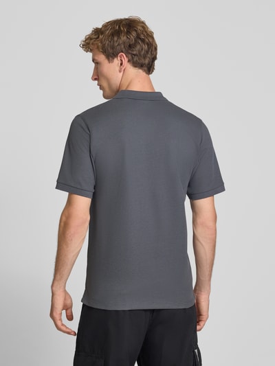 Męski model nosi koszulkę polo Slim Fit Poloshirt mit Label-Stitching Modell 'AUSTIN' od JACK & JONES, szara mieszanka materiałów z bawełną, krój slim fit, kołnierzyk polo, wyhaftowane logo, długość tyłu w rozmiarze M: 70 cm, widok całej sylwetki od tyłu.