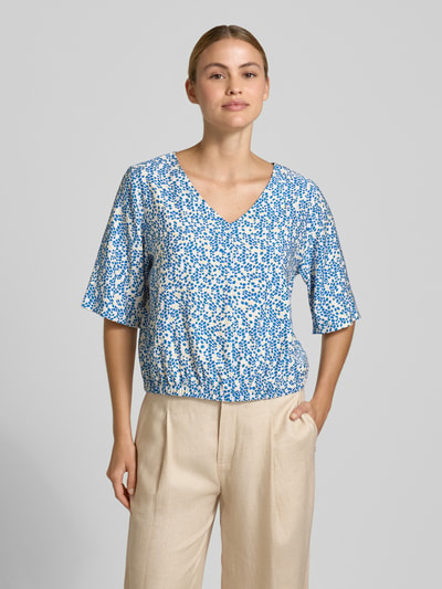 Frauenmodel trägt Relaxed Fit Blusentop aus Viskose-Mix von s.Oliver RED LABEL, blau-weißes florales Allover-Muster, Satin-Struktur, Ganzkörperansicht von vorne.