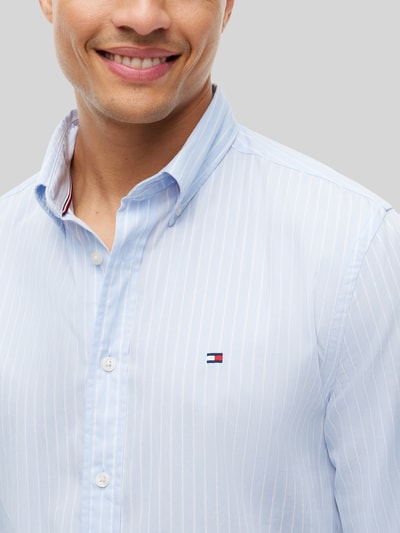 Männermodel trägt Body Fit Freizeithemd aus reiner Baumwolle von Tommy Hilfiger in Hellblau mit feinen Streifen, Nahaufnahme Oberkörper. Herren Freizeithemd von Tommy Hilfiger.