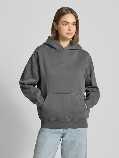 Vrouwenmodel draagt Pegador Oversized Hoodie met logo en kangoeroezak Model 'CLARITA', katoenmix, grijs, vooraanzicht bovenlichaam.