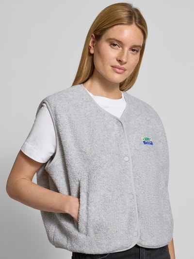 Frauenmodel trägt Weste mit Rundhalsausschnitt Modell 'HOKTOWN' von American Vintage in Hellgrau, lockerer Schnitt, Teddyfell, Nahaufnahme Oberkörper.