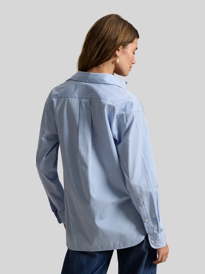 Vrouwenmodel draagt 'Hemdbluse mit Knopfleiste' van Polo Ralph Lauren, lichtblauw katoen, losse pasvorm, labelstiksel, rugaanzicht.