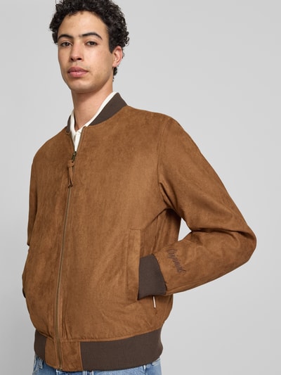 Mężczyzna model nosi bomberka in Leder-Optik mit Stehkragen von Jack & Jones, brązowy kolor, zamek błyskawiczny, wpuszczane kieszenie, krój regular fit, długość tyłu w rozmiarze M: 64 cm, szerokość ramion w rozmiarze M: 45 cm, szerokość klatki piersiowej w rozmiarze M: 52 cm, długość rękawów w rozmiarze M: 67 cm, Ganzkörperansicht z przodu