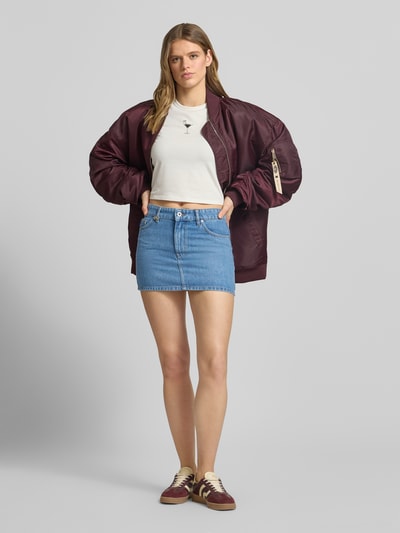 Frauenmodel trägt Regular Fit Jeansrock aus Baumwoll-Mix Modell 'GALANIE_B' von Hugo Blue in Blau mit 5-Pocket-Design, Mini-Länge, Label-Patch und verdecktem Reißverschluss, Denim-Optik, Ganzkörperansicht von vorne.