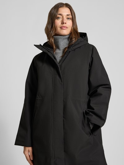 Vrouwenmodel draagt zwarte Relaxed Fit Functiemantel met capuchon model 'FRANCINE' van Selected, dames functiemantel, borst-nahaufnahme.
