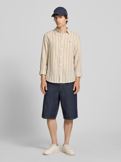 Männermodel trägt Regular Fit Freizeithemd aus Leinen-Baumwoll-Mix von Tommy Jeans, Mehrfarbig, Gestreift, Logo-Schriftzug, Ganzkörperansicht von vorne.