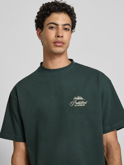 Männermodel trägt T-Shirt mit Label-Stitchings und Rundhalsausschnitt von PROHIBITED in Dunkelgrün, Reine Baumwolle, Regular-Fit, Nahaufnahme Oberkörper. Rückenlänge bei Größe M: 65 cm.