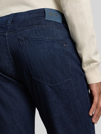 Männermodel trägt Slim Fit Jeans mit Seiden-Anteil Modell 'Chuck' von BRAX, dunkles Blau, 5-Pocket-Design, Nahaufnahme Rückansicht, elastischer Baumwoll-Mix mit Viskose-Seiden-Anteil, Knopf-Reißverschluss, Bundweite 44 cm, Innenbeinlänge 81 cm.
