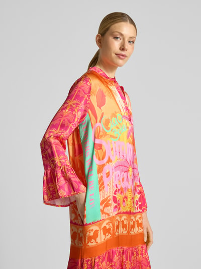 Kobiece modelka nosi sukienka midi z wiskozy z dekoltem w serek model 'Orange Palm' od miss goodlife, linia a, wzór na całej powierzchni, długość tyłu w rozmiarze s 130 cm, szerokość w rozmiarze s 53 cm, długość rękawów w rozmiarze s 58 cm, kolor pomarańczowy i różowy, widok z przodu, ujęcie do pasa.