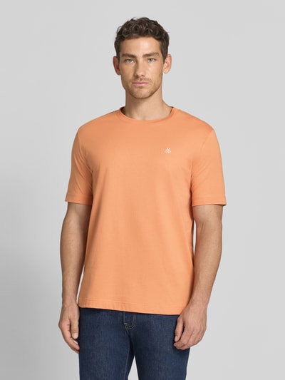 Männermodel trägt Regular Fit T-Shirt aus reiner Baumwolle von Marc O'Polo in Orange, unifarben mit Logo-Print, Ganzkörperansicht von vorne.