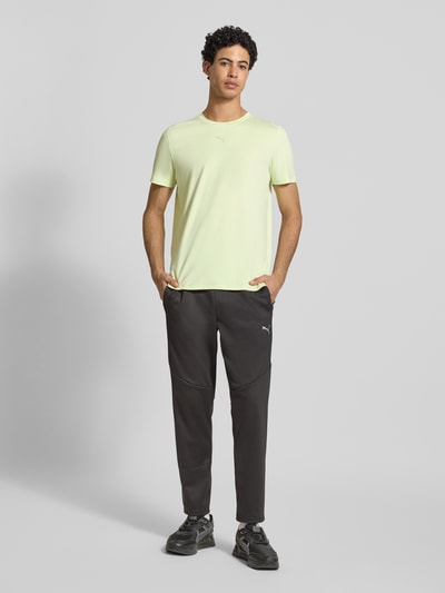 Männermodel trägt Regular Fit T-Shirt mit Logo-Print Modell 'Cloudspun' von PUMA PERFORMANCE, Rundhalsausschnitt, pastellgelb, Herren T-Shirt, Regular-Fit, Rückenlänge 65 cm bei Größe M, glatte Oberfläche, Ganzkörperansicht von vorne.