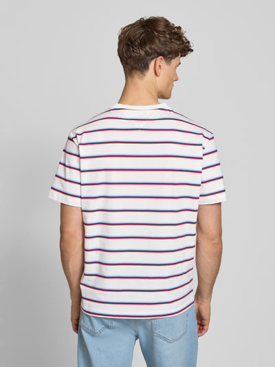 Männermodel trägt Regular Fit T-Shirt aus reiner Baumwolle von Tommy Jeans mit Optik:Allover-Muster, gestreift, Ganzkörperansicht Rückansicht.