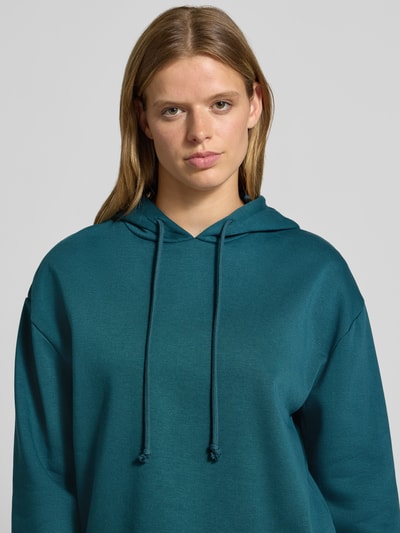 Frauenmodel trägt Regular Fit Hoodie aus Baumwoll-Mix Modell 'CHILLI' von PIECES in Petrol mit glatter Struktur, Nahaufnahme Oberkörper. Damen Hoodie von PIECES.