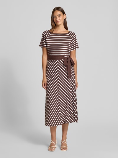 Frauenmodel trägt Midikleid mit U-Boot-Ausschnitt und Bindegürtel von More & More, braun-weiß gestreift, Baumwoll-Modal-Mix, taillierter Schnitt, Ganzkörperansicht von vorne.