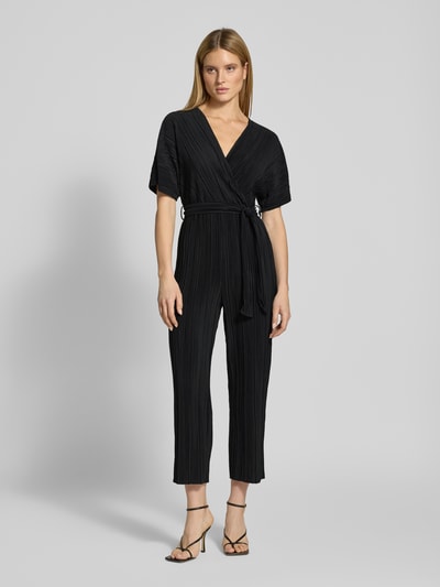 Vrouwenmodel draagt Regular fit jumpsuit met V-hals model 'Olinda' van YAS in zwart met plisséstructuur en afneembare stoffen riem, volledige lichaamsvooraanzicht.