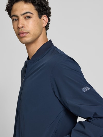 Männermodel trägt Regular Fit Bomberjacke mit College-Kragen Modell 'BELVEDERE' von Pepe Jeans in Dunkelblau, Label Patch, Nahaufnahme Oberkörper.