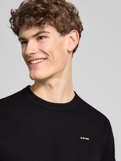 Männermodel trägt Regular Fit T-Shirt mit Strukturmuster von G-Star Raw, Schwarz, Rundhalsausschnitt, Logo, Nahaufnahme Oberkörper.