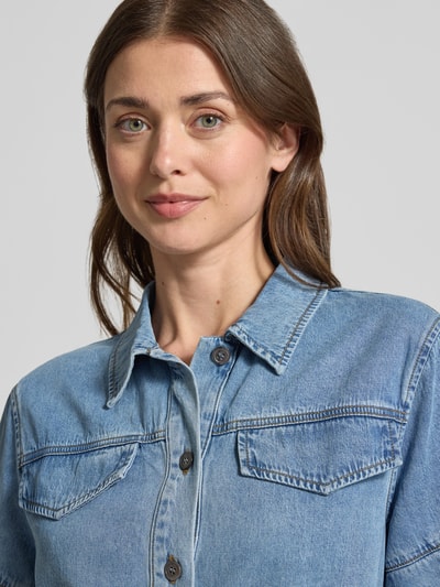 Frauenmodel trägt Boxy Fit Jeansbluse mit Brusttaschen Modell 'LAIKA' von SUNCOO PARIS aus Lyocell-Baumwoll-Mix, Nahaufnahme Oberkörper.