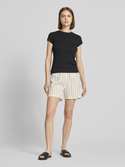 Frauenmodel trägt Regular Fit Shorts aus reiner Baumwolle Modell 'TIZIANA' von Only mit Optik: Allover-Muster, gestreift, 5-Pocket-Design, Tunnelzug und elastischem Bundabschluss, cremeweiß mit schwarzen Streifen, strukturierte Oberfläche, Ganzkörperansicht von vorne.
