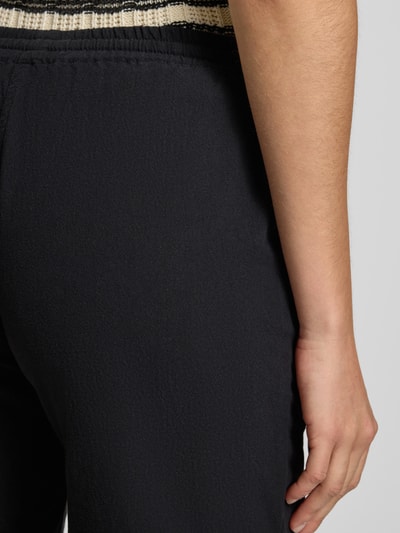 Frauenmodel trägt Shorts mit elastischem Bund Modell 'Cissie' von Soyaconcept aus reiner Baumwolle, schwarze Farbe, Detailaufnahme Rückenansicht.