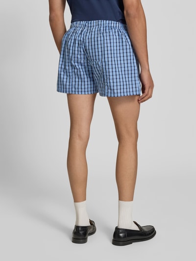 Männermodel trägt Boxershorts aus reiner Baumwolle von VETEMENTS, kariert, lockere Passform, elastischer Bund, Label-Patch, Ganzkörperansicht Rückansicht.