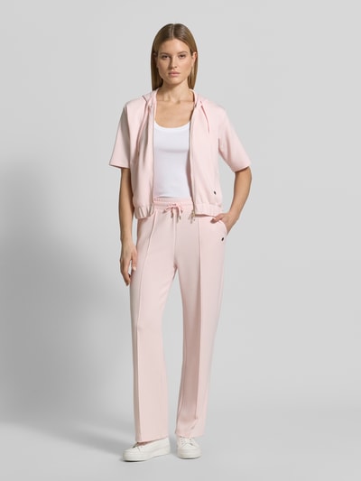 Modelka kobieca nosi Sweatpants mit Label-Applikation Modell 'Talila' od JOOP!, jasnoróżowy, prosty krój, elastyczny pas, materiał z modalem, szerokość w rozmiarze 36: 40 cm, długość nogawki wewnętrznej: 80 cm, zdjęcie całej sylwetki z przodu.