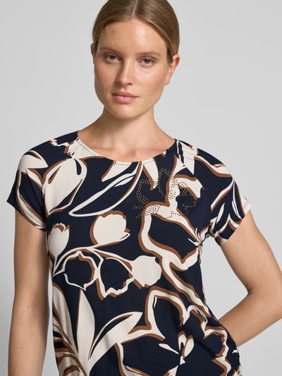 Frauenmodel trägt Regular Fit T-Shirt aus Viskose-Mix von Betty Barclay mit abstraktem Blumenmuster in Blau, Braun und Weiß, Nahaufnahme Oberkörper. Damen T-Shirt von Betty Barclay.
