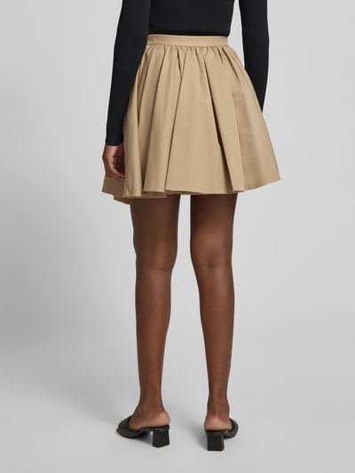 Frauenmodel trägt Minirock mit Lyocell-Anteil von Self-Portrait in Beige, A-Linie, elastischer Bund, seitliche Eingrifftaschen, Ganzkörperansicht Rückansicht. Gesamtlänge 47 cm bei Größe S, Bundweite 34 cm.