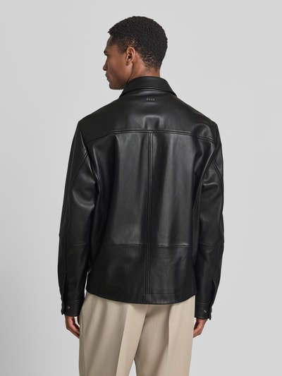 Männermodel trägt Regular Fit Lederjacke Modell 'JOBAN' von BOSS Orange, schwarzes Echtleder, Umlegekragen, Rückansicht Ganzkörperansicht.