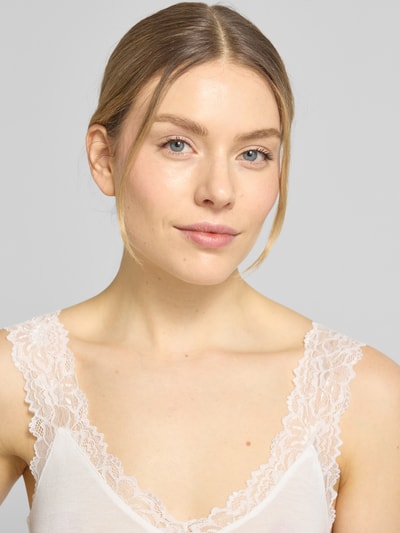 Frauenmodel trägt Slim Fit Tank Top aus Viskose-Mix Modell 'ROSA' von Vero Moda, Optik: Unifarben, Rüschen-Applikation, V-Ausschnitt, breite Träger, Materialverarbeitung: Feinripp, Nahaufnahme Oberkörper.