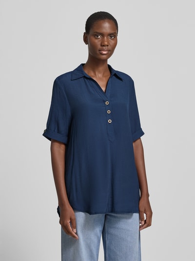 Frauenmodel trägt Relaxed Fit Bluse aus Viskose-Mix mit Umlegekragen von Apricot, Knopfleiste, Halbarm, semitransparentes Design, verlängerte Rückseite, dunkelblauer Stoff, glatte Textur, Rückenlänge bei Größe S 81 cm, Ärmellänge 28 cm, Ganzkörperansicht von vorne.