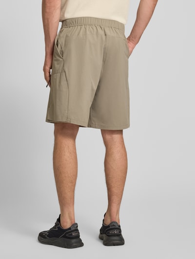 Männermodel trägt Relaxed Fit Cargoshorts mit Label-Schriftzug Modell 'GLOBE CARGO' van BOSS Green, uni, elastische taille, knoopsluiting, zakken, ganzkörperansicht rückansicht