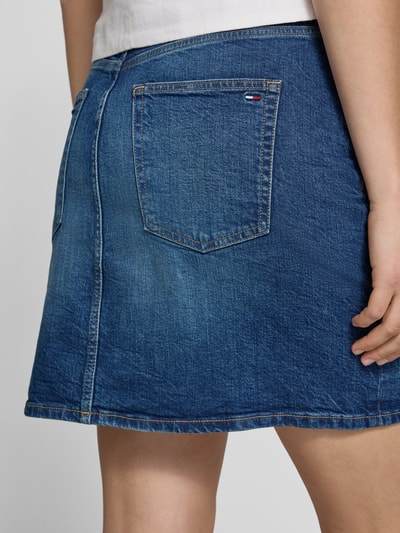 Frauenmodel trägt Regular Fit Jeansrock aus Baumwoll-Mix Modell 'MOM' von Tommy Jeans in Denim-Optik mit Logo-Stitching, Ausgestellt, Midi-Länge, 5-Pocket-Design, Gürtelschlaufen und Label-Patch, Materialverarbeitung Twill, Detailaufnahme Rückansicht.