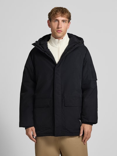 Männermodel trägt Parka mit Pattentaschen Modell 'Stanwood' von Carhartt Work In Progress in Schwarz, Reißverschluss, Regular Fit, Ganzkörperansicht von vorne.