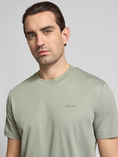 Männermodel trägt T-Shirt mit Rundhalsausschnitt von CK Calvin Klein in hellem Grün, Baumwoll-Mix, Regular Fit, Nahaufnahme Oberkörper.