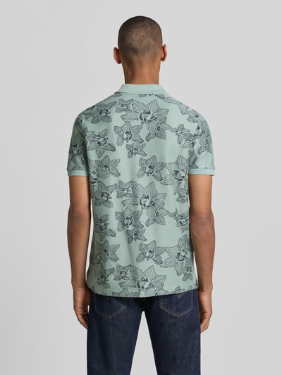 Männermodel trägt Slim Fit Poloshirt mit floralem Allover-Print von Lerros aus Reiner Baumwolle, hellgrün mit Polokragen, Ganzkörperansicht Rückansicht.