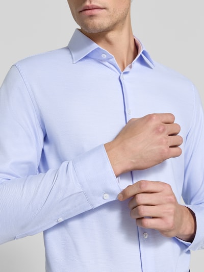 Mężczyzna model nosi Slim Fit Businesshemd aus reiner Baumwolle Modell 'New Kent Patch' von Seidensticker w jasnoniebieskim kolorze, widoczna faktura materiału, zbliżenie na górną część ciała, Herren Businesshemd von Seidensticker